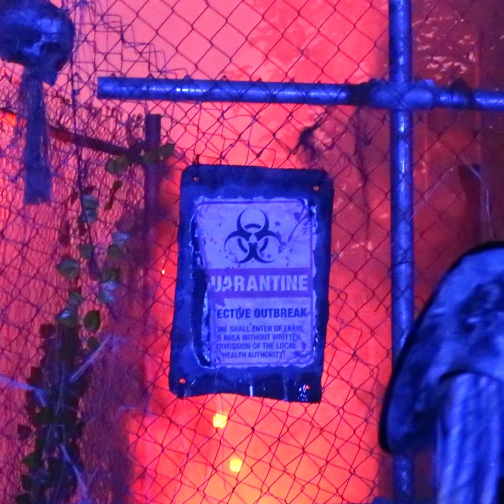 Cartel de cuarentena tras una verja iluminada en rojo en La Isla Maldita