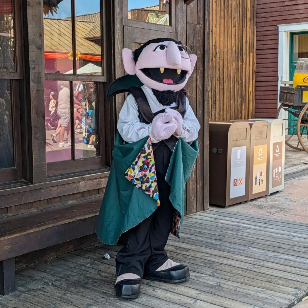Conde Draco posando con capa verde en una calle de PortAventura