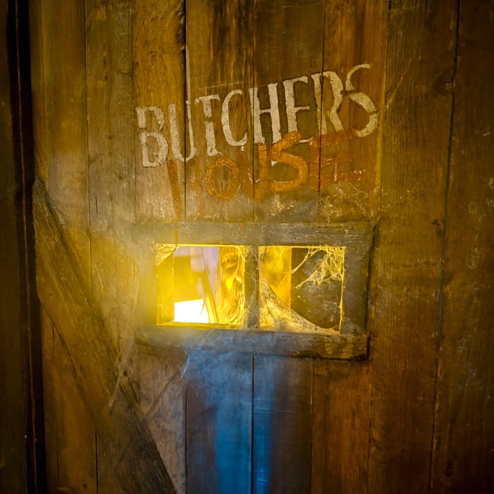 Puerta de madera con el rótulo Butchers y una ventana iluminada